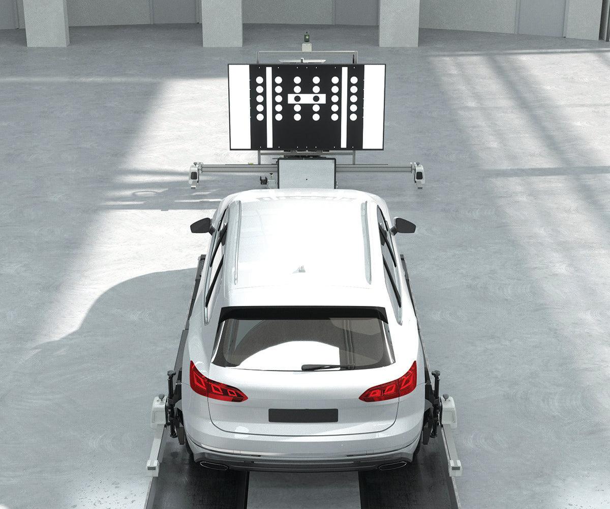 A vehicle positioned in front of ADAS calibration equipment for calibration of ADAS cameras and radar sensors